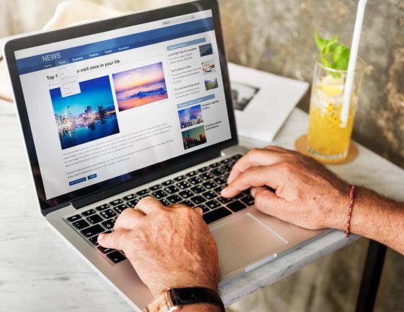 Un homme consulte le classement sites web de l'actualité sur son ordinateur portable, avec un verre de jus à ses côtés.