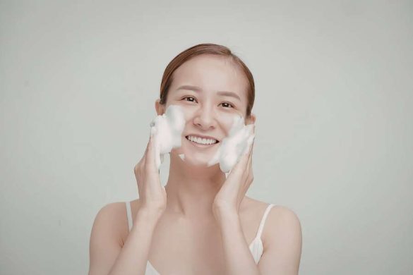 Femme nettoyant son visage avec mousse dans une routine beauté minimaliste