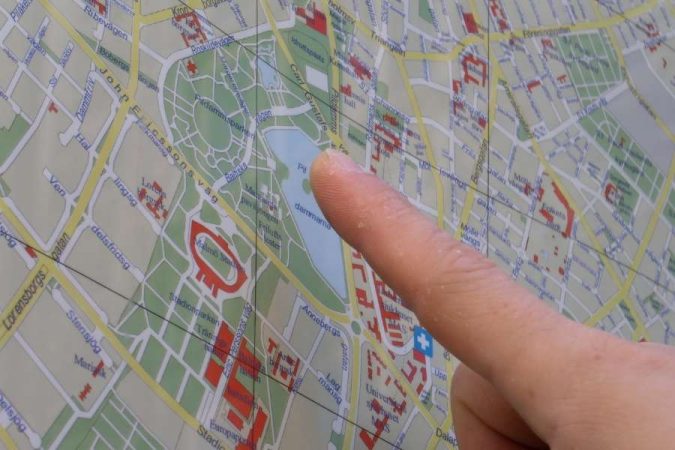 Un doigt pointe une destination précise sur une carte urbaine détaillée, à la recherche de destinations méconnues à explorer.